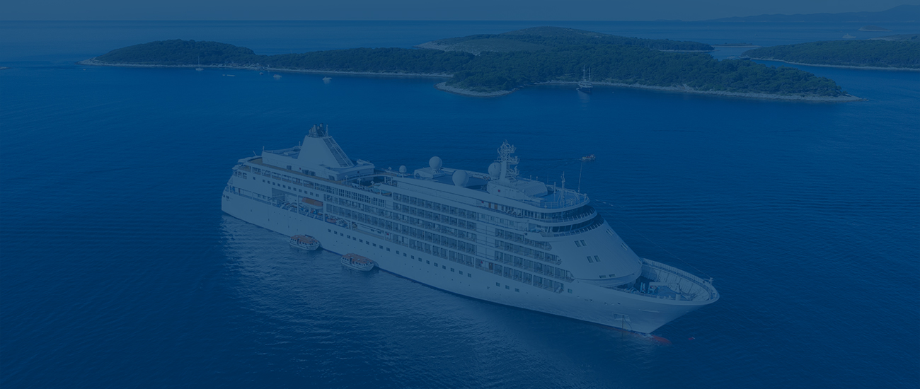 Photograph of a cruise ship with an island in the background, the image has a blue filter.